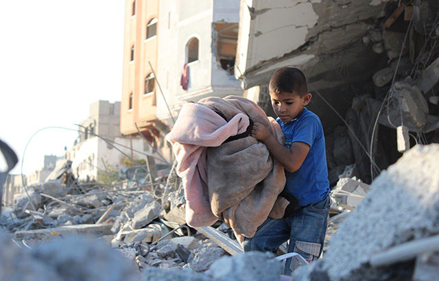 A child in Gaza walking around rubble
