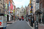 A street in Dublin with signs for shops and restaurants ending in a church