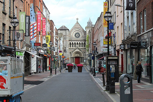 A street in Dublin with signs for shops and restaurants ending in a church