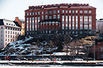 Psychologicum building of the University of Helsinki on a hill above a snow covered road.