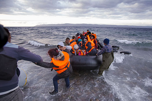 Syrian migrants / refugees arrive from Turkey on boat through sea with cold water near Molyvos, Lesbos on an overload dinghy. Leaving Syria that has war
