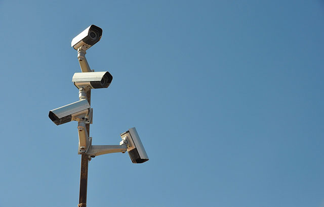 Surveillance cameras on a mast against a blue sky