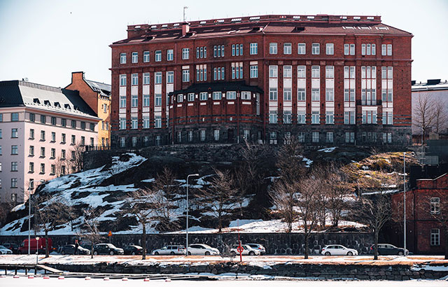 Psychologicum building of the University of Helsinki on a hill above a snow covered road.