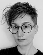Head and shoulder photo of Maja Grundler in black and white. She has short hair and is wearing glasses and a black top.