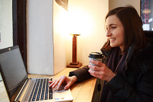 Student in a cafe reading from a laptop