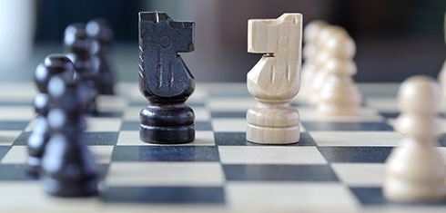 A black knight and a white knight facing each other on a chess board