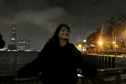Teja Shah standing by the harbor in Hong Kong at night