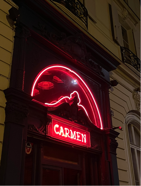 Photo of the entrance to Le Carmen Paris nightclub with a red neon sign