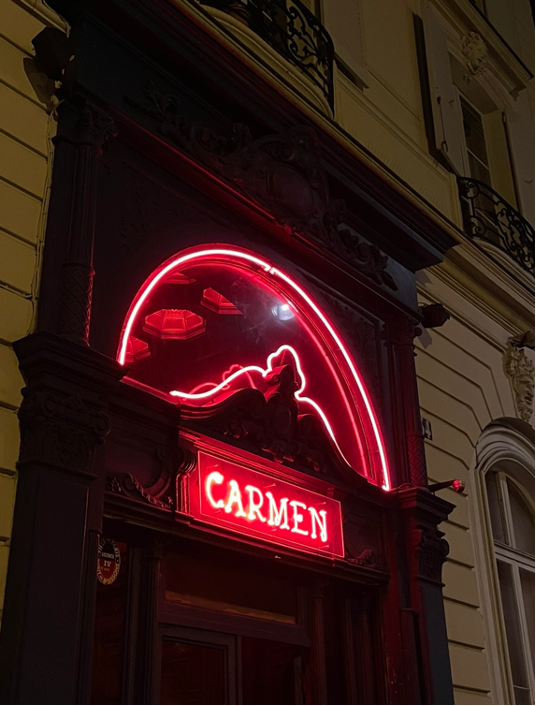 Photo from the entrance of the nightclub Le Carmen Paris with the sign illuminated with red neon lights