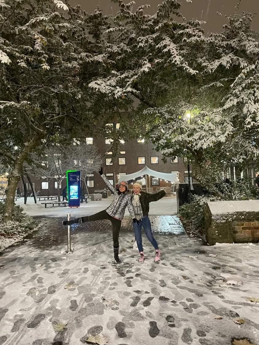 Lisa and her friend posing for the camera in a snowy university campus
