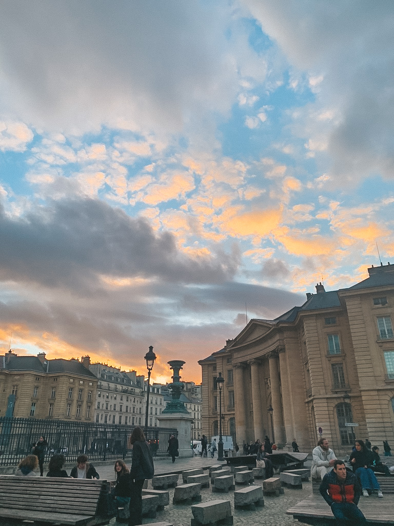 Students sitting in the courtyard of Pantheon Sorbonne University in Paris. Sunset in the background