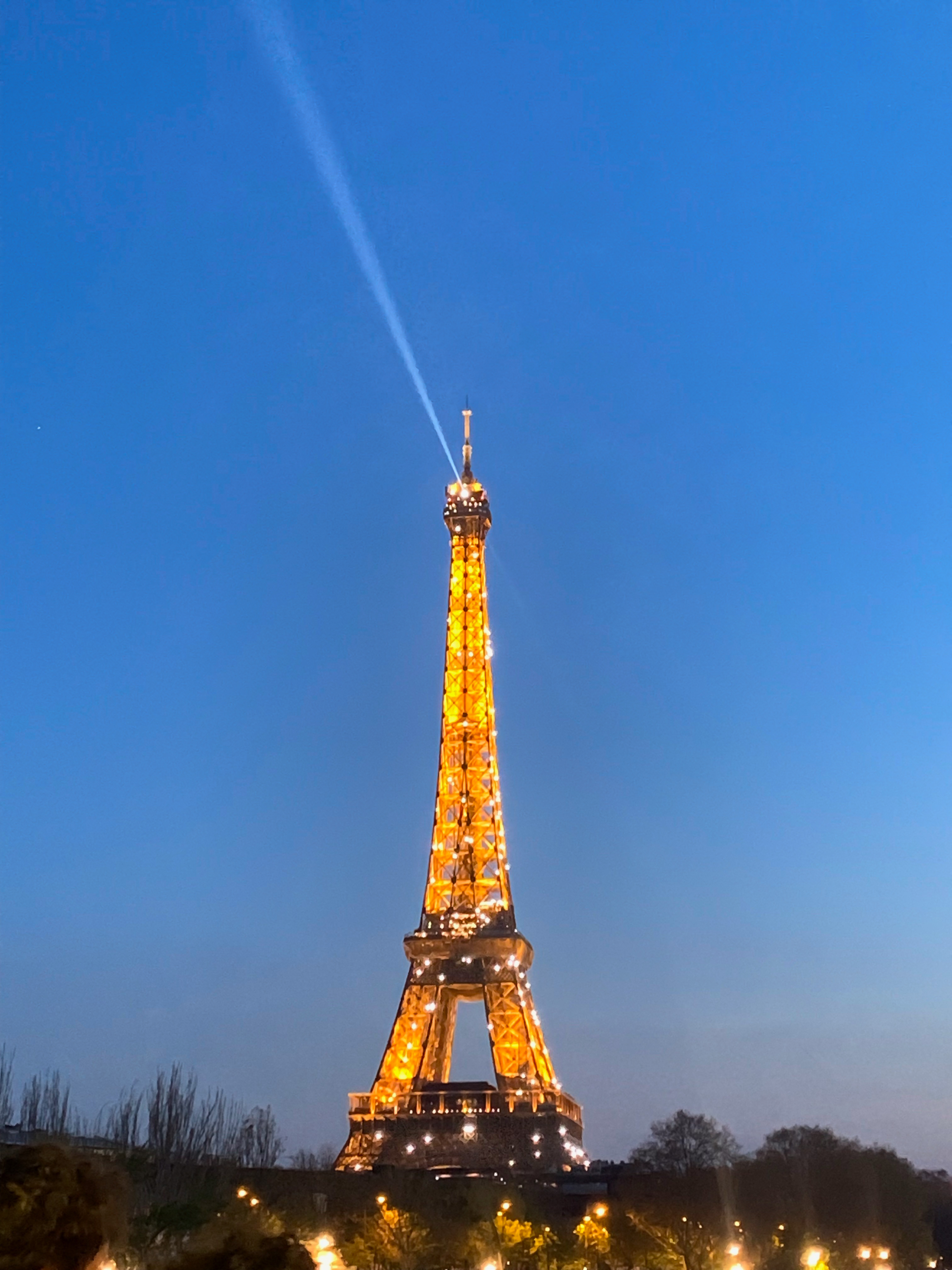 Lit Eiffel Tower in the evening with a blue sky