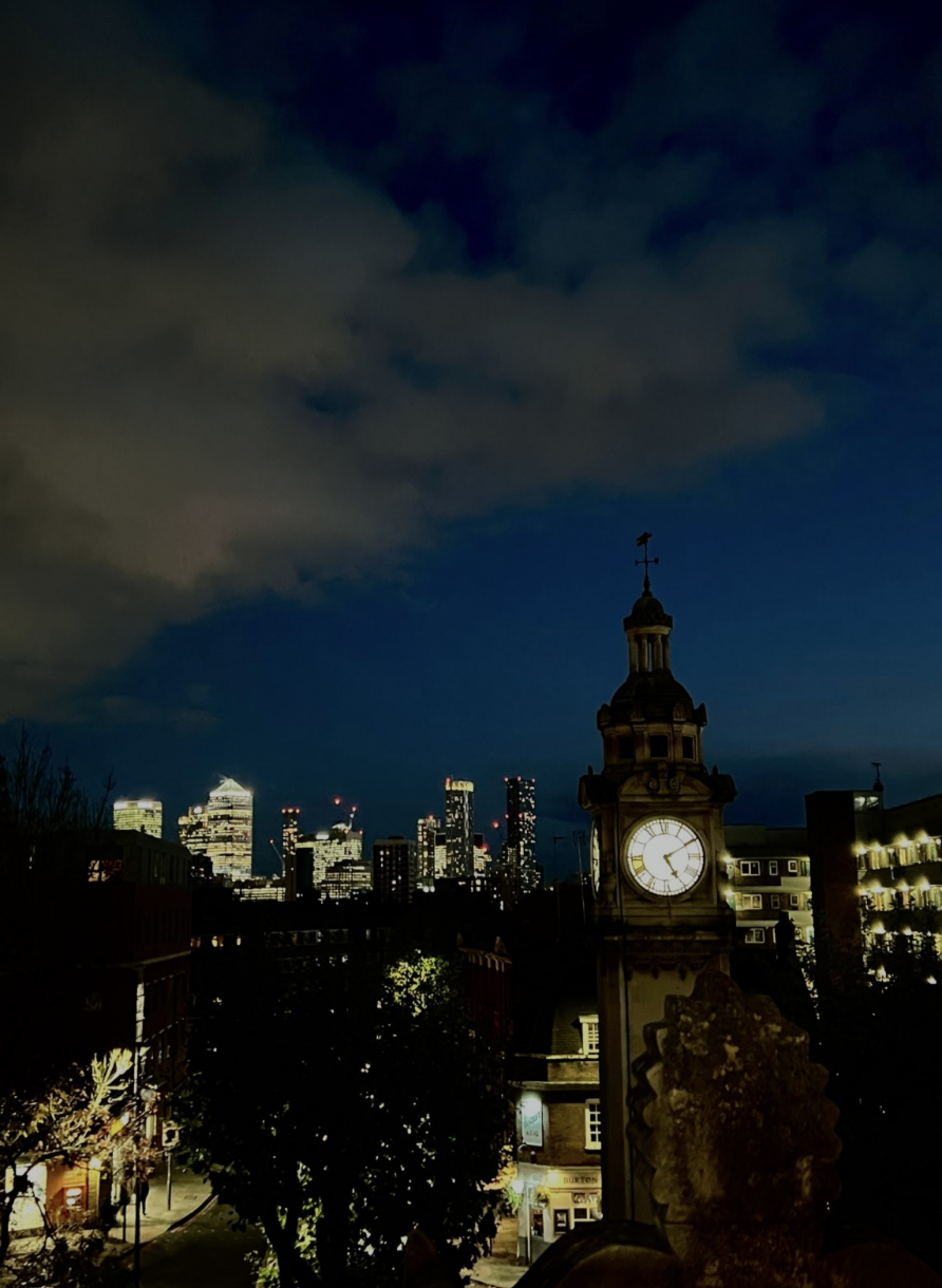 Clocktower in Mile End Campus at night with London skyline in the background