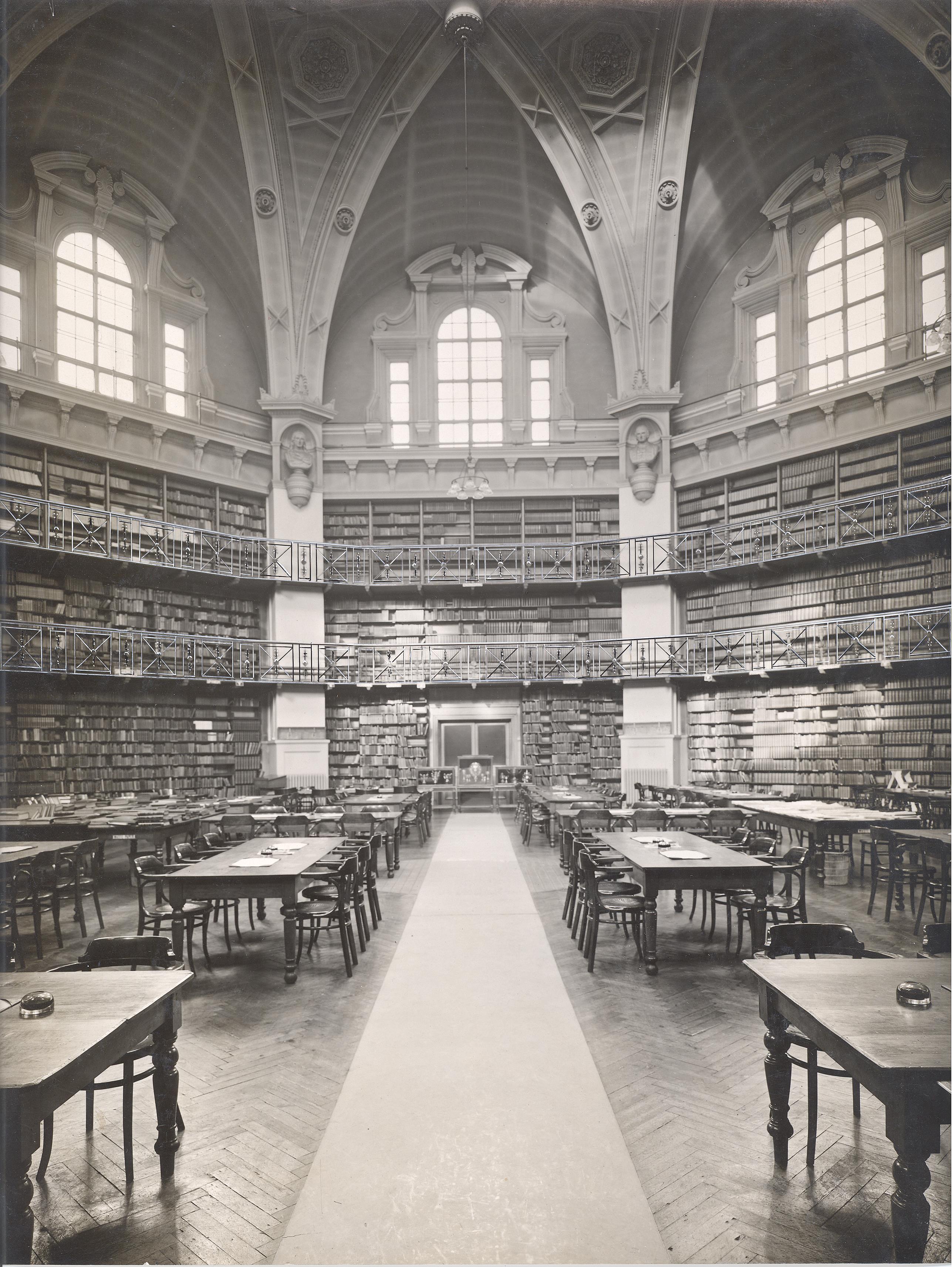 The Octagon laid out as a college library with books on the shelves and tables with ash trays