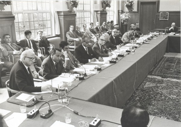 Black and white photograph of men sitting around a table with microphones places at intervals.  The image is from 1968