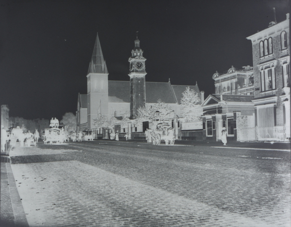 Photographic negative of People's Palace, frontage on Mile End Road, showing cobbled road with horse drawn carriages and St Benets Church in background