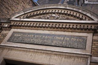 Quotation in gilt lettering on a grey stone plaque above the door of the Museum and Library Block at St Bartholomew's Hospital in London