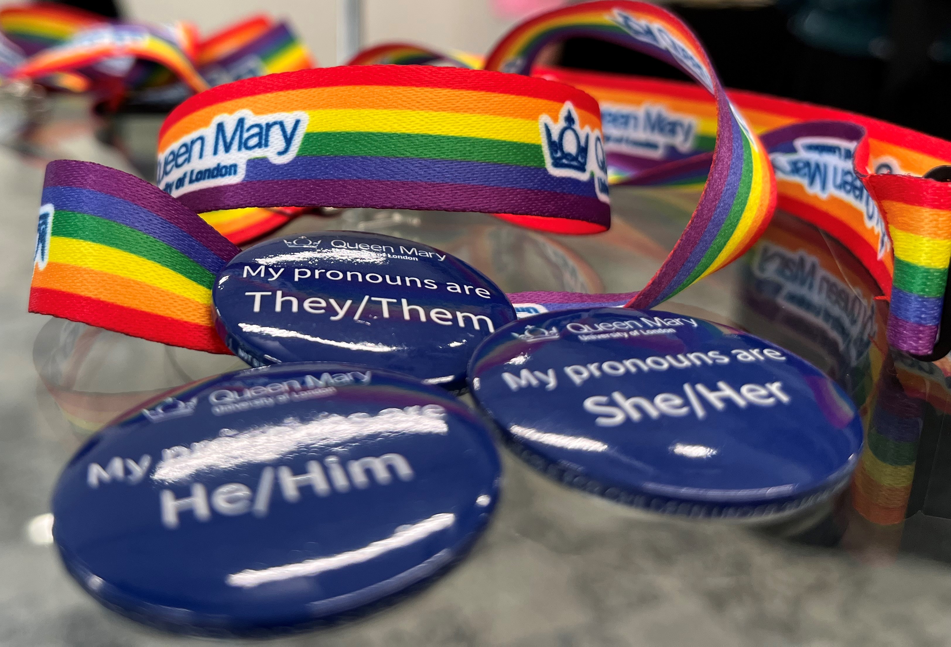 Photo of a selection of Queen Mary pronoun badges and rainbow lanyards