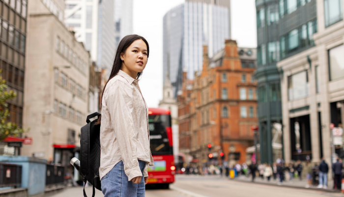 A woman standing in front of london red bus and buildings