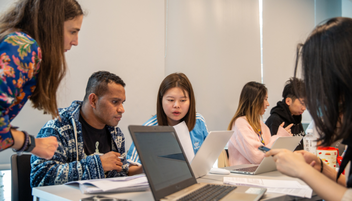 Students sitting working together on laptops in a classroom