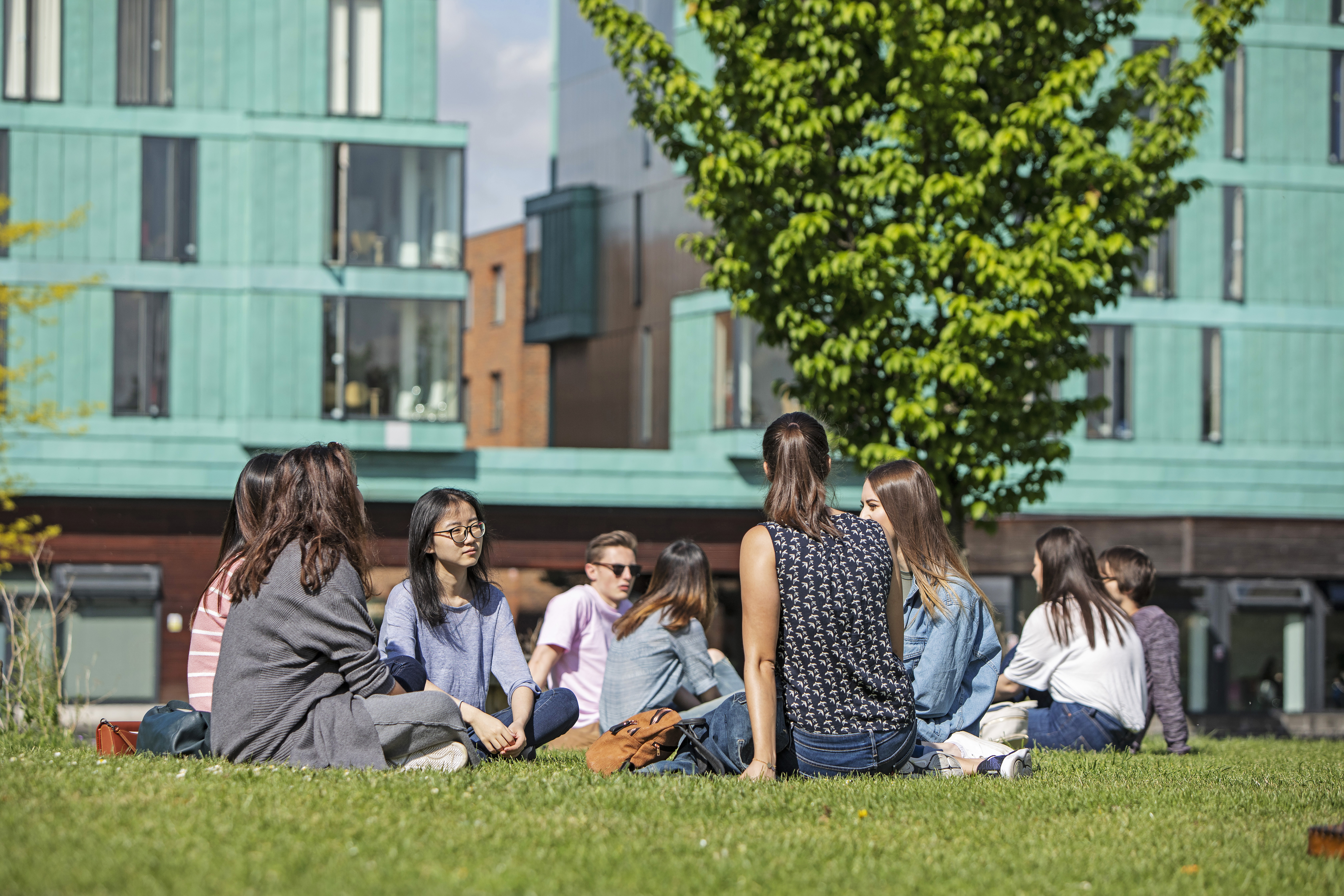 Group of students sitting down on our Queen Mary University of London Mile End campus