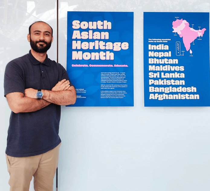 Man standing next to a poster which reads 'South Asian Heritage Month'