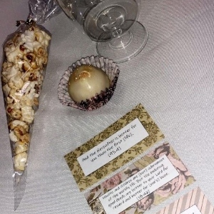 Popcorn cone, chocolate, glass and quote card on dinner table