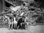 Children sitting among rubble 