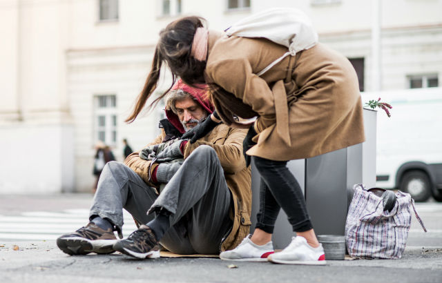 A woman offers help to a homeless man