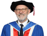 Picture of Peter in blue graduation gown and black felt graduation hat