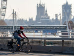 A cyclist wearing a facemask cycles past Parliament