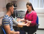 Female GP takes blood pressure of male patient