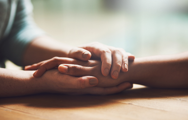 Two people holding hands in comfort.