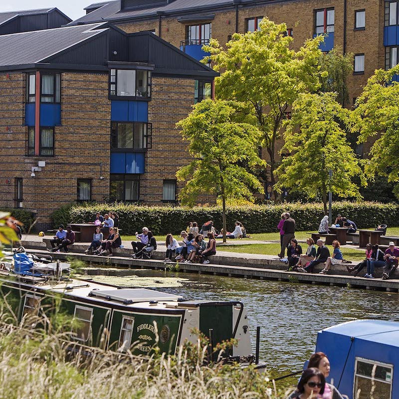 People sitting by the canal on Mile End campus