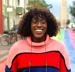 Headshot of Ife Akinroyeje, a young Black woman wearing a pink, red and blue striped jumper.