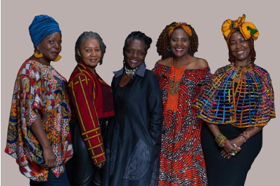 The authors of 'Our Stories Told By Us' - five Black women - stand together smiling. Four of the women wear bright, geometric patterned clothing.