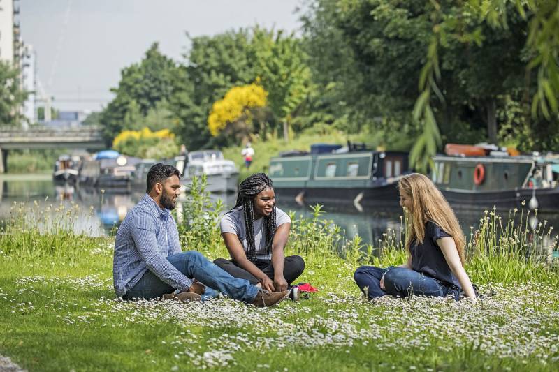 Three students sitting by a canal