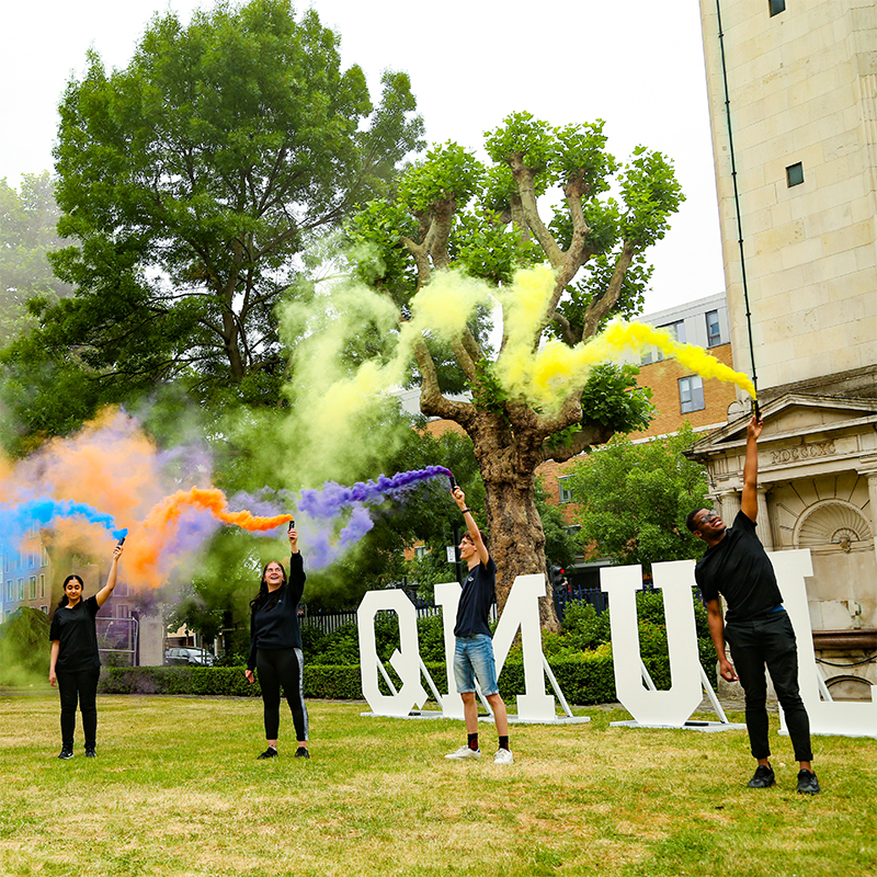 students holding up colourful smoke