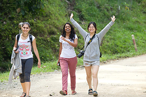 three female students walking along forest path