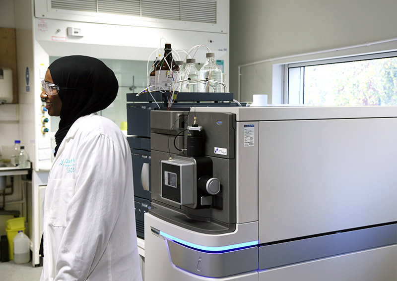 student standing next to Mass Spectrometer