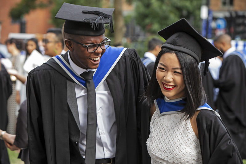 Two students laughing in their graduation gowns