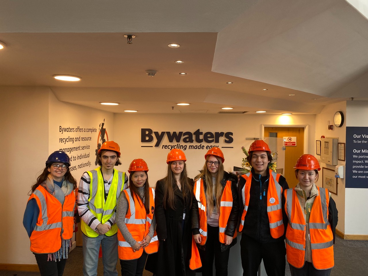 A group of students and staff wearing high vis and helmets at Bywaters for the Materials Recovery Facility Tour.