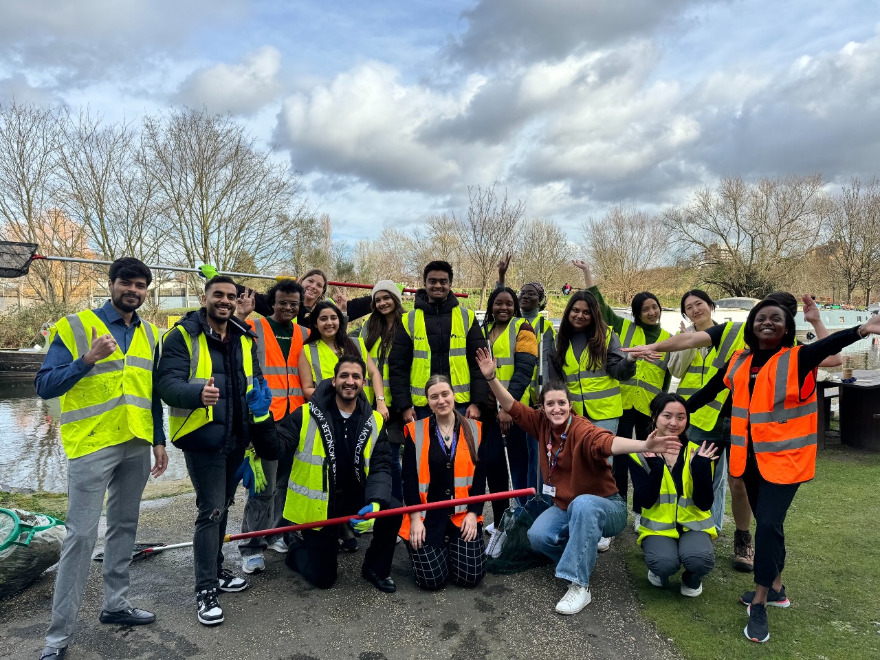 A large group of students with litter pickers and nets posing next to Regent's Canal on the Mile End Campus after cleaning the canal as part of Climate Action Week.