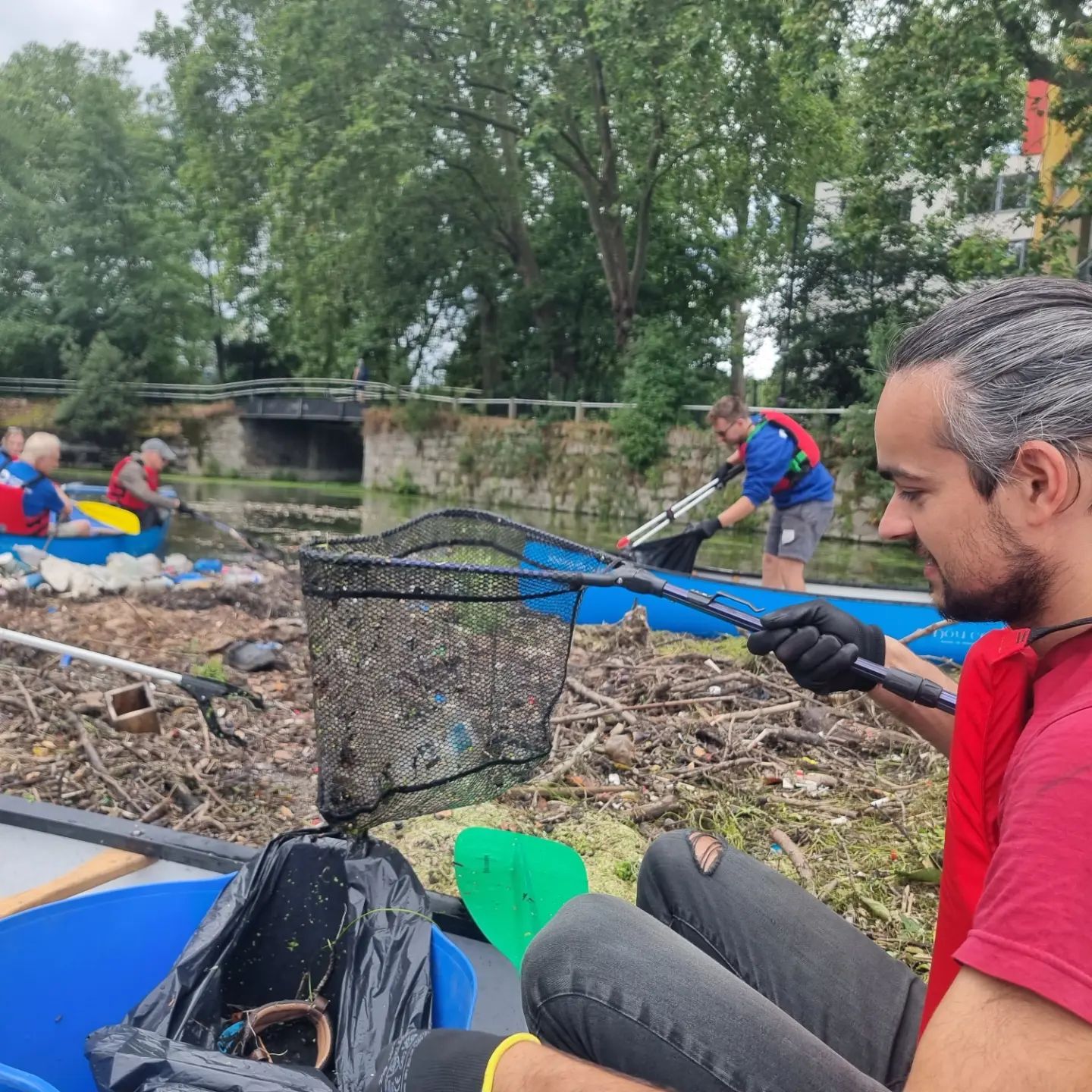 A student in a canoe collecting rubbish from a trash island in the River Lea.