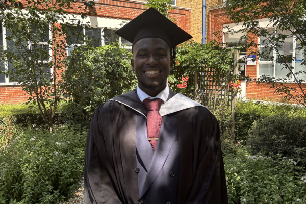 Ade in graduation attire, smiling.