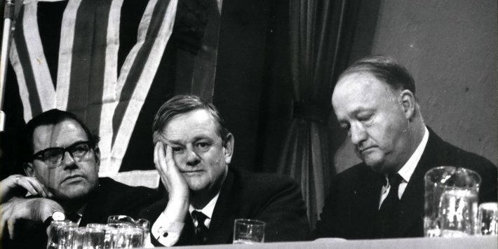 A black and white photo of three of the candidates to be the next leader of the Conservative Party at its conference in Blackpool in 1963. It shows Reggie Maudling, Quintin Hailsham, and Rab Butler sitting next to each other. They all look unhappy and Hailsham is resting his face on his right hand.