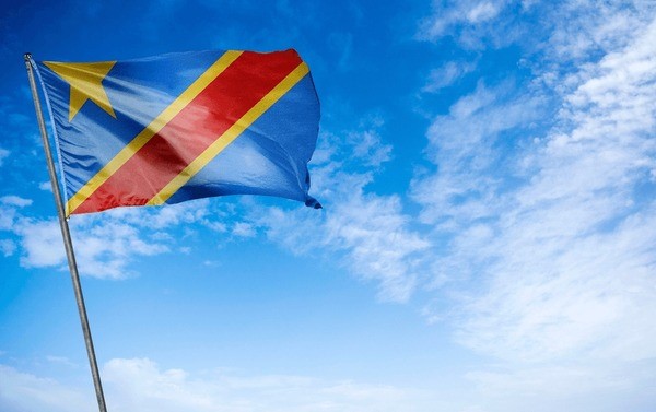 The flag of the DR Congo flying against a blue sky.