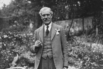 Labour's first Prime Minister, Ramsay MacDonald, standing in a garden, clutching his lapel, looking into the camera.