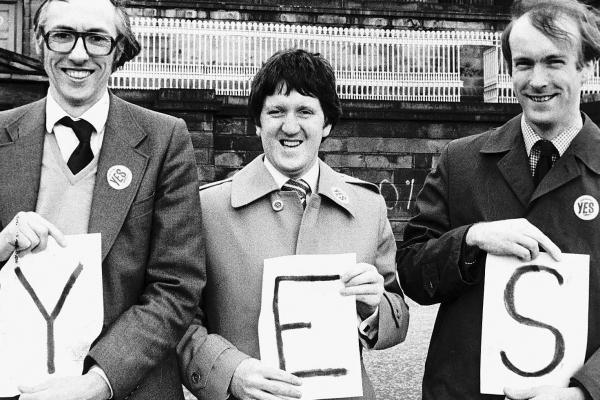 Photo of Donald Dewar and George Robertson holding 'YES' sign in front of Old Royal High School