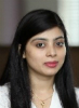 A portrait photo of Meghna Chandra. She wears a white blouse and has very long straight dark hair.